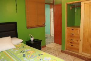 a bedroom with green walls and a bed and a dresser at LUGAR DE DESCANSO in Ica