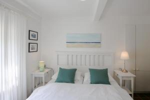 um quarto com uma cama branca e almofadas verdes em Landhaus Risum em Risum-Lindholm