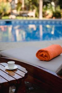 an orange towel and a cup on a bench next to a pool at Suites La Hacienda in Puerto Escondido