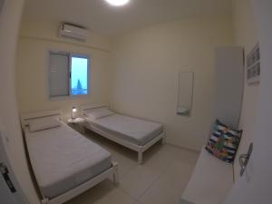 ein kleines Zimmer mit 2 Betten und einem Fenster in der Unterkunft Beach House Itaguá Apartamento 2 Excelente localização ar-condicionado, churrasqueira, piscina e sauna in Ubatuba