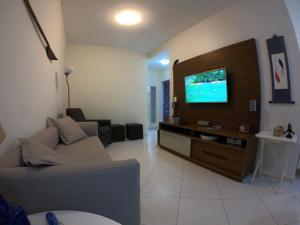 ein Wohnzimmer mit einem Sofa und einem Flachbild-TV in der Unterkunft Beach House Itaguá Apartamento 2 Excelente localização ar-condicionado, churrasqueira, piscina e sauna in Ubatuba