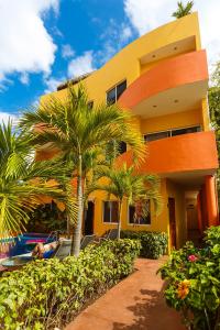 a yellow house with palm trees and a swimming pool at Kaam Accommodations in Puerto Morelos