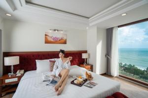 uma mulher sentada numa cama num quarto de hotel em Apus Hotel em Nha Trang