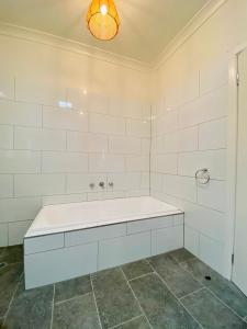a white bathroom with a tub and a light at Kanasta Caravan Park in Rye
