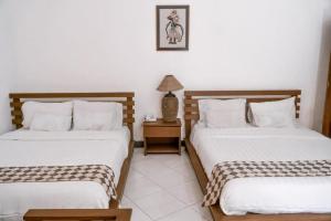a bedroom with two beds and a night stand with a lamp at Grand Cepu Hotel in Cepu