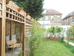 - un jardin avec un banc en bois dans la cour dans l'établissement Mapesbury Hostel London, à Londres