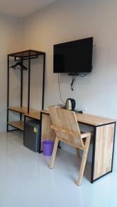 Elle comprend un bureau avec une télévision et une chaise en bois. dans l'établissement Suwannolhotel, à Khon Kaen