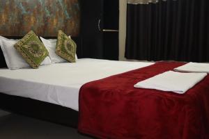 a bed with red and white sheets and pillows at The Salvation Army RED SHIELD GUEST HOUSE in Kolkata