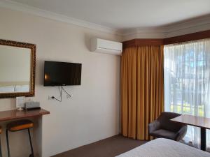 ein Hotelzimmer mit einem Bett, einem TV und einem Fenster in der Unterkunft Motel Margeurita in Queanbeyan