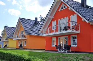 uma casa vermelha e amarela com cadeiras em frente em Ferienhaus Müritzbrise / OG-Appartement em Marienfelde