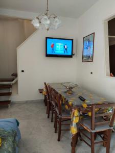 einen Esstisch mit Stühlen und einen TV an der Wand in der Unterkunft Casa Santa Gemma in Camaiore