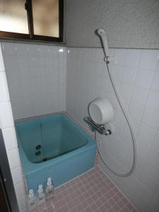 a bathroom with a blue tub with a shower at Ikkenya Tsushima in Okayama