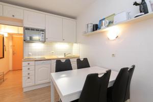 uma cozinha com uma mesa branca e cadeiras pretas em Berolina Wohnung 805 Traum Ostseeblick em Dahme