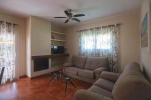 un soggiorno con divano e ventilatore a soffitto di Villas La Barrosa a Chiclana de la Frontera