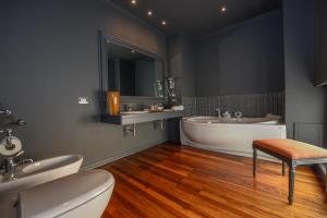 盧卡的住宿－The Tuscanian Hotel，一间带两个盥洗盆、浴缸和卫生间的浴室