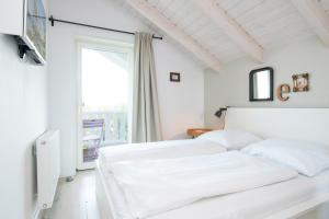 ein weißes Schlafzimmer mit 2 Betten und einem Fenster in der Unterkunft Seepark Süssau Ferienhaus Seeteufel 3 in Süssau