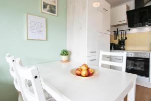 - une cuisine blanche avec un bol de pommes sur une table dans l'établissement Kieler Straße 23 Wohnung 5, Kleine Oase, à Grömitz