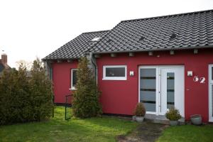 une maison rouge avec une porte blanche dans l'établissement Lenster Möwennest, à Lenste