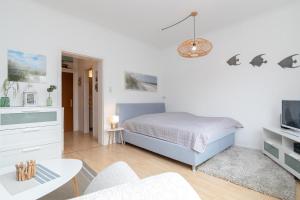 een witte slaapkamer met een bed en een woonkamer bij Weidenweg 25 Weidennest in Grömitz