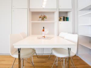 uma mesa de jantar branca com cadeiras brancas e uma garrafa de vinho em Tannenburg Wohnung 110 em Grömitz