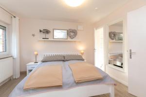a white bedroom with a large bed in a room at Bungalow Eiland in Grömitz