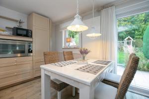 eine Küche mit einem weißen Tisch und Stühlen sowie einem Fenster in der Unterkunft Seehus I in Grömitz