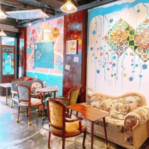 a waiting room with chairs and tables and a mural at Old Door Hostel & Bar in Taipei
