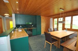 a kitchen with green cabinets and a wooden table at Ferienwohnungen Hotel Alpina in Adelboden