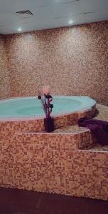 Elle comprend un grand bain à remous avec un vase de fleurs. dans l'établissement Olymp Hotel, à Bansko