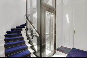 una escalera con moqueta azul y una puerta de cristal en Maison Labruyère Bordeaux - Jardin Public, en Burdeos