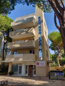 a tall building with trees in front of it at Family Residence Nuova Orchidea in Riccione