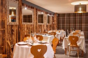 a restaurant with white tables and chairs and mirrors at Hotel L'Ecrin des Neiges in La Joue du Loup