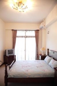 um quarto com uma cama, uma televisão e uma janela em Yangpin House Homestay em Hualien