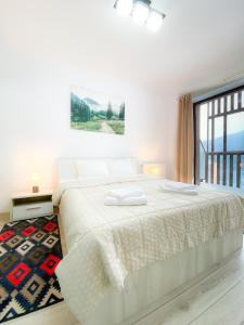 Un dormitorio blanco con una cama grande y una ventana en Forest View Oasis, en Brasov