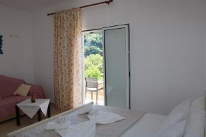 - une chambre avec un lit et une porte coulissante en verre dans l'établissement PENELOPE 2, à Dhërmi