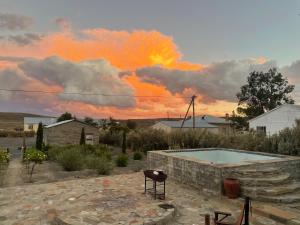 a sunset over a backyard with a pool and a table at Die Prokureurshuis in Sutherland