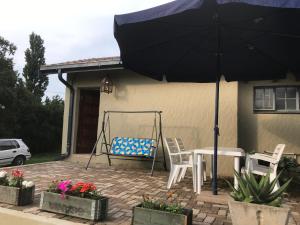 een patio met een tafel en stoelen en een parasol bij Blooming Nice Stay in Harrismith