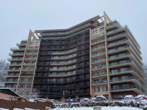 un edificio de apartamentos alto con nieve en el suelo en Forest View Oasis, en Brasov