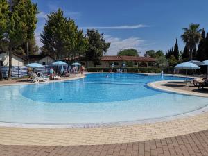 uma grande piscina azul com pessoas sentadas à sua volta em Mobile home Viareggio - including airco- Camping Paradiso - G008 em Viareggio