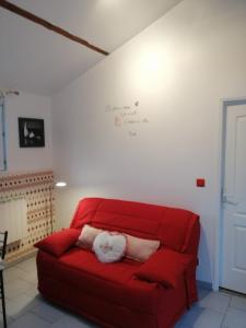 Un sofá rojo con dos almohadas blancas. en gite proche etretat, en Tourville-les-Ifs