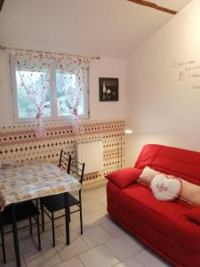 uma sala de estar com um sofá vermelho e uma mesa em gite proche etretat em Tourville-les-Ifs