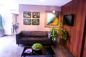 a living room with a leather couch and a table at Hotel Alpha in Uberlândia