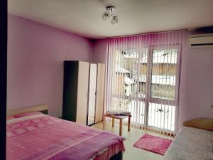 Schlafzimmer mit rosa Wänden, einem Bett und einem Fenster in der Unterkunft Apartment Daiv in Saparewa Banja