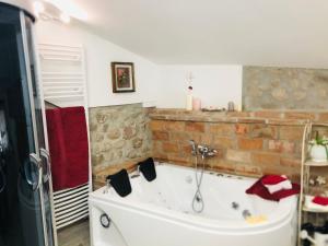 a bath tub in a bathroom with a brick wall at GardaBeds Adults Only in Castelnuovo del Garda