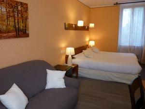 une chambre d'hôtel avec deux lits et un canapé dans l'établissement Logis Hôtel Restaurant Belle Rive, à Najac