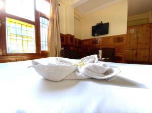 a white towel sitting on top of a bed at Hotel Sanjeevny in Bajaura