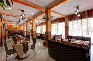 a dining room with tables and chairs and windows at Hotel Sanjeevny in Bajaura