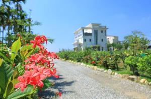 a road with red flowers in front of a building at Gully Orchard Homestay in Jialin