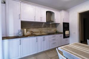 a kitchen with white cabinets and a sink and a table at Transylvanian Apt. w/ lrg. terrace and parking - KarpatenHaus in Braşov