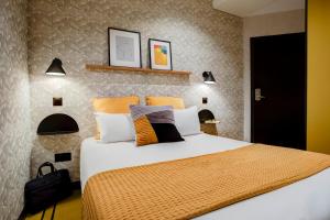 ein Schlafzimmer mit einem großen Bett und orangefarbenen und weißen Kissen in der Unterkunft Republik Hotel in Lyon